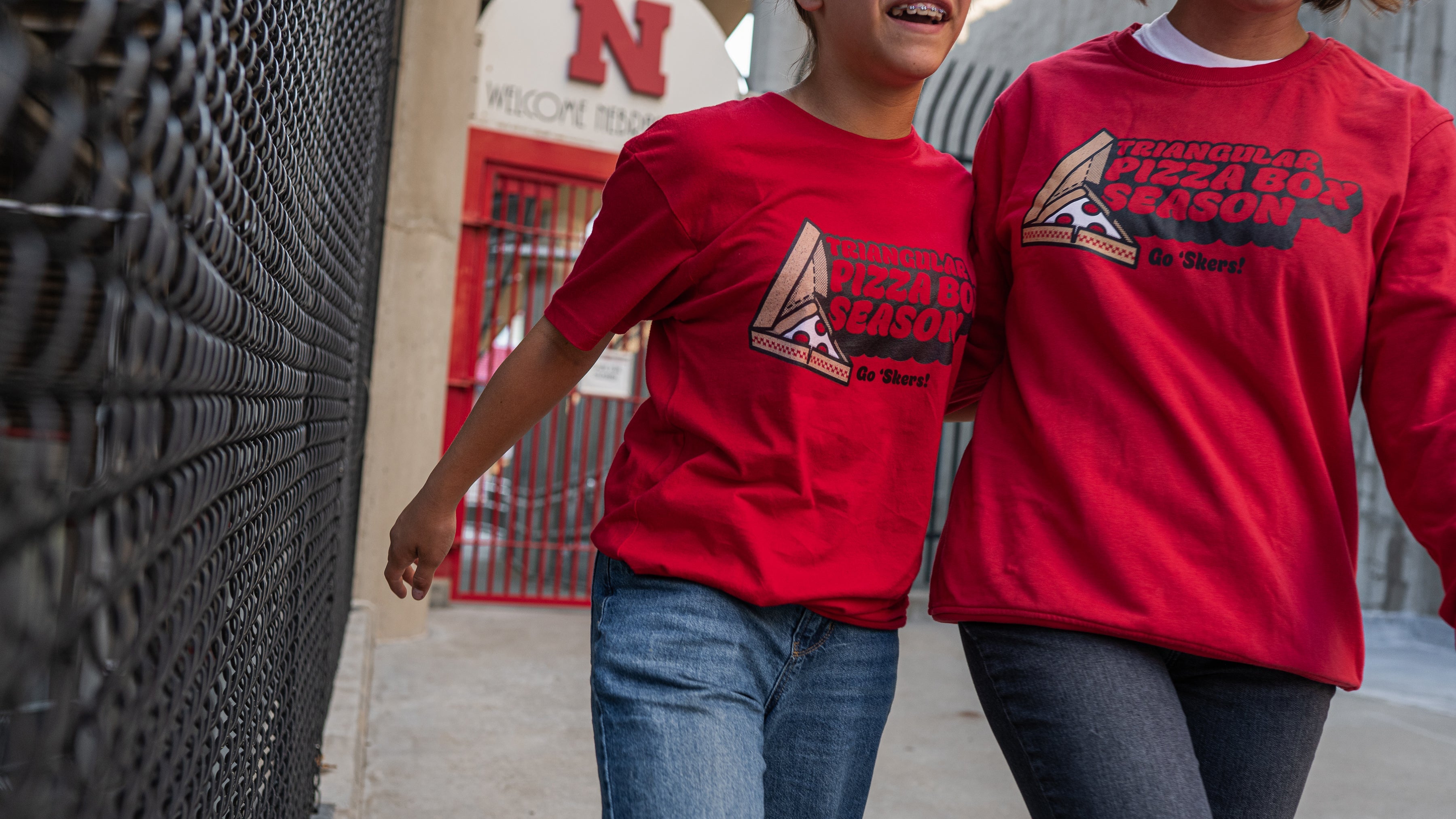 two people wearing matching Triangular Pizza Box Season shirts.